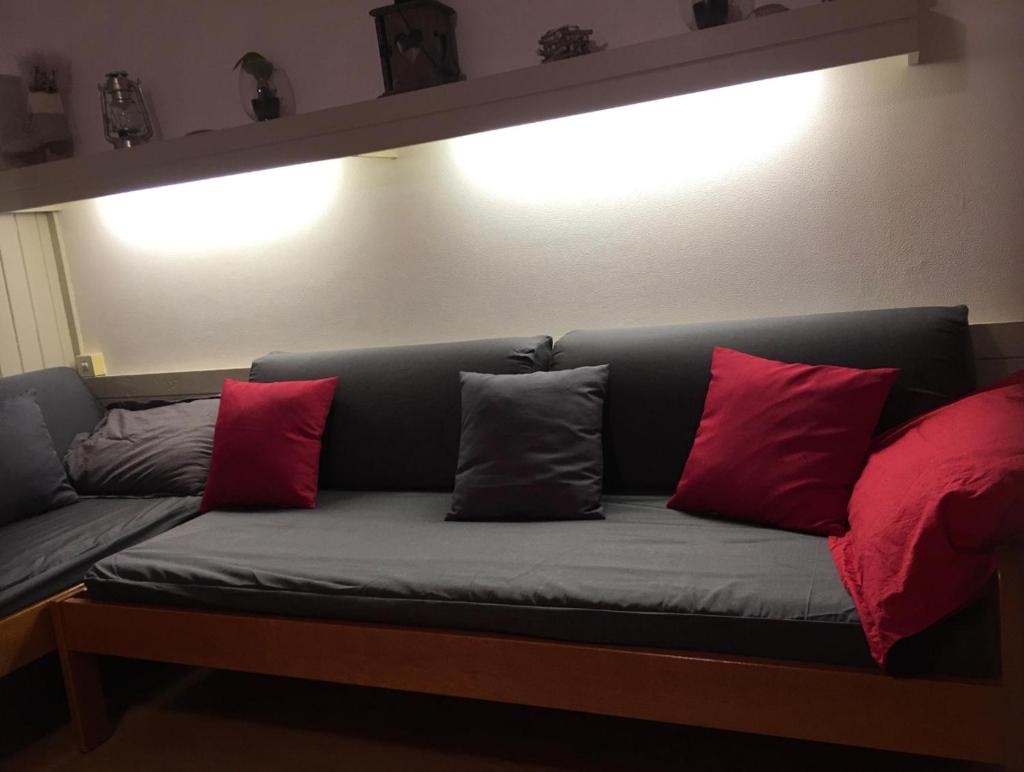 - un canapé avec 4 oreillers rouges dans l'établissement APPARTEMENT 804, à Saint-Étienne-en-Dévoluy