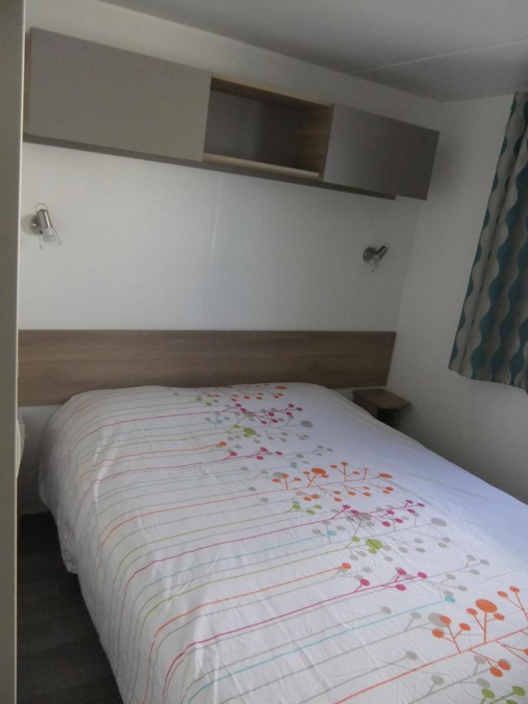 - un lit fleuri dans une chambre dans l'établissement Assist' Mobil Home 289 - Mobil Home élégance 2 chambres 6 personnes, à Onzain