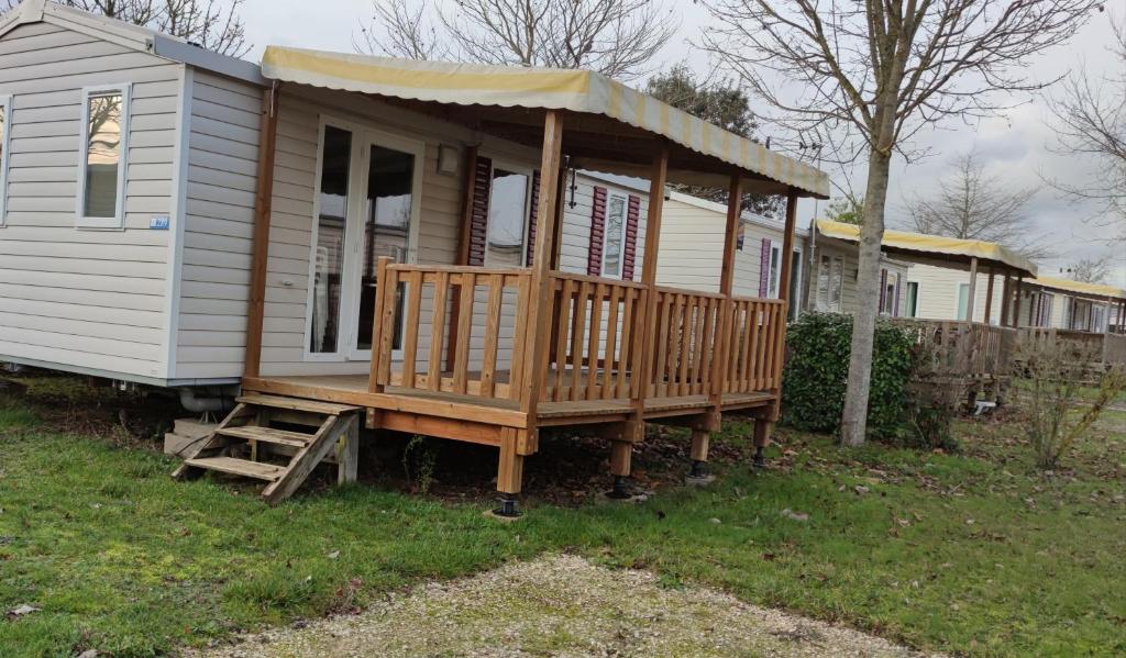 une petite maison avec une terrasse couverte sur une cour dans l'établissement Assist' Mobil Home 289 - Mobil Home élégance 2 chambres 6 personnes, à Onzain