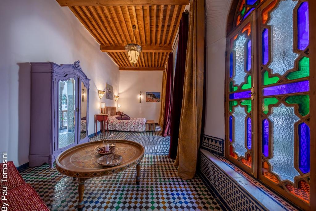 Cette chambre dispose d'une table et d'un vitrail. dans l'établissement Riad Fes Nass Zmane, à Fès