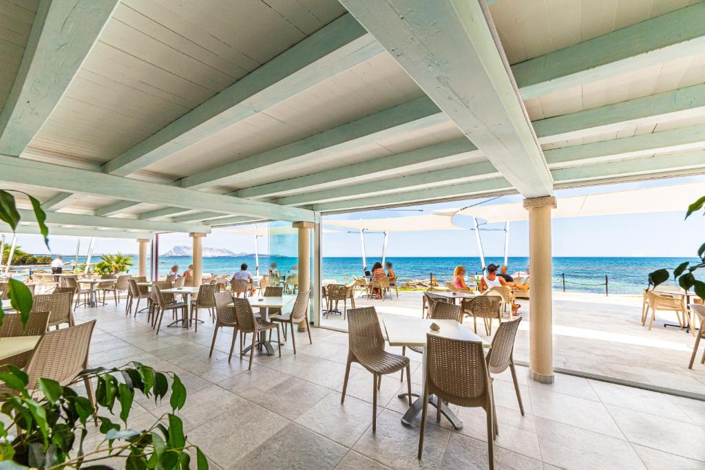 un restaurant sur la plage avec tables et chaises dans l'établissement Hotel L'Esagono, à San Teodoro