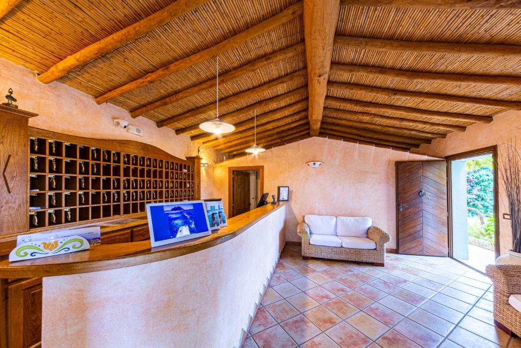 un bar dans une pièce avec un canapé et une chaise dans l'établissement Hotel L'Esagono, à San Teodoro