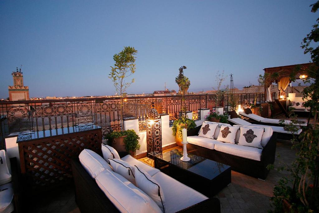 - un toit-terrasse avec des canapés blancs et des lumières dans l'établissement Riad Assakina, à Marrakech