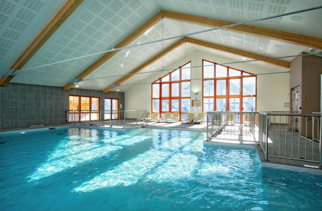 une grande piscine intérieure d'eau bleue dans l'établissement Résidence Prestige Odalys Rochebrune Les Cimes, à Orcières