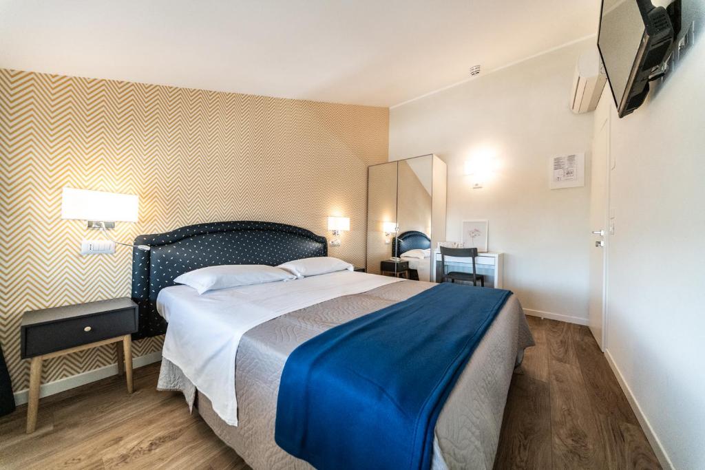 une chambre avec un grand lit avec une couverture bleue dans l'établissement Hotel Kiss, à Riccione