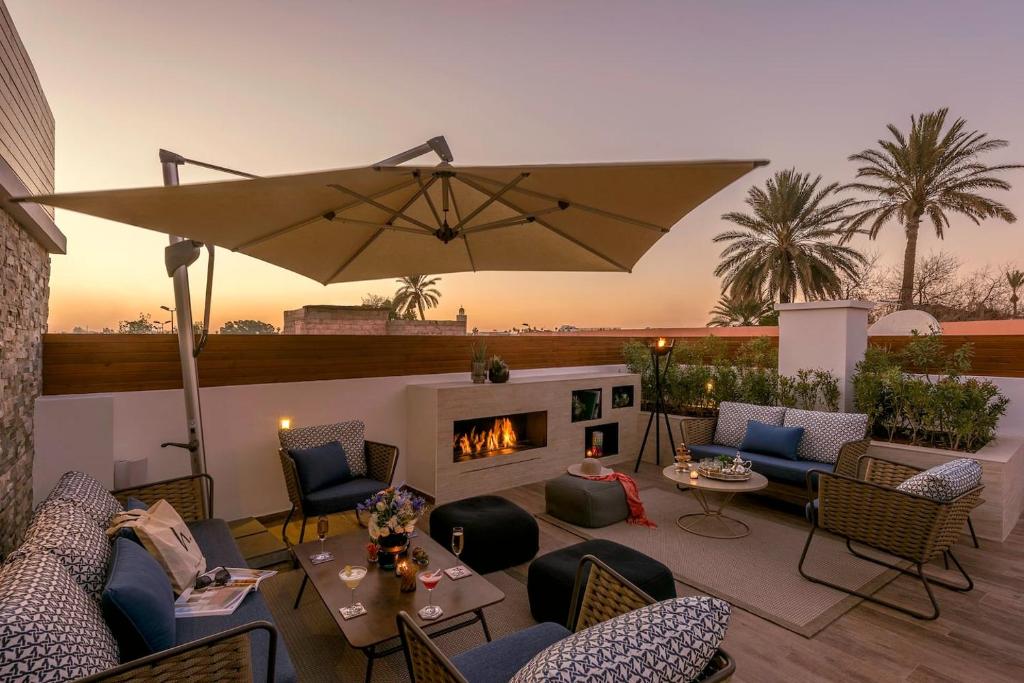 un patio avec des chaises, une cheminée et un parasol dans l'établissement La Brillante Marrakech, à Marrakech