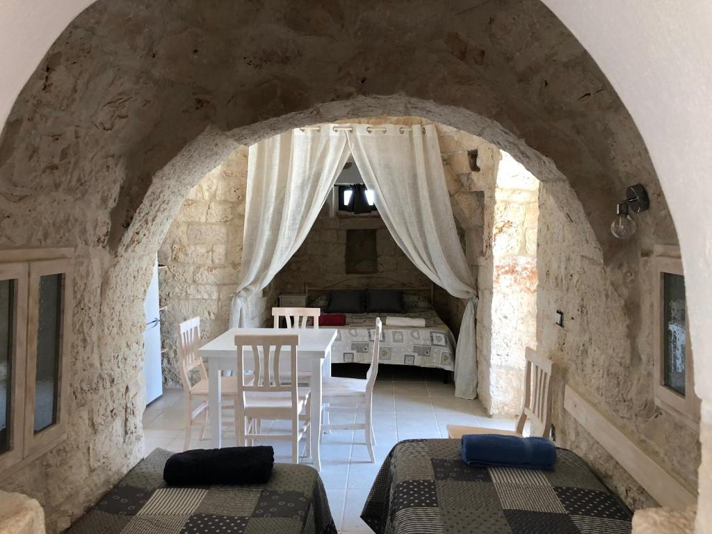 Cette chambre comprend deux lits et une table avec des chaises. dans l'établissement TRULLO PARCOMONSIGNORE CON PISCINA PRIVATA, à San Vito dei Normanni