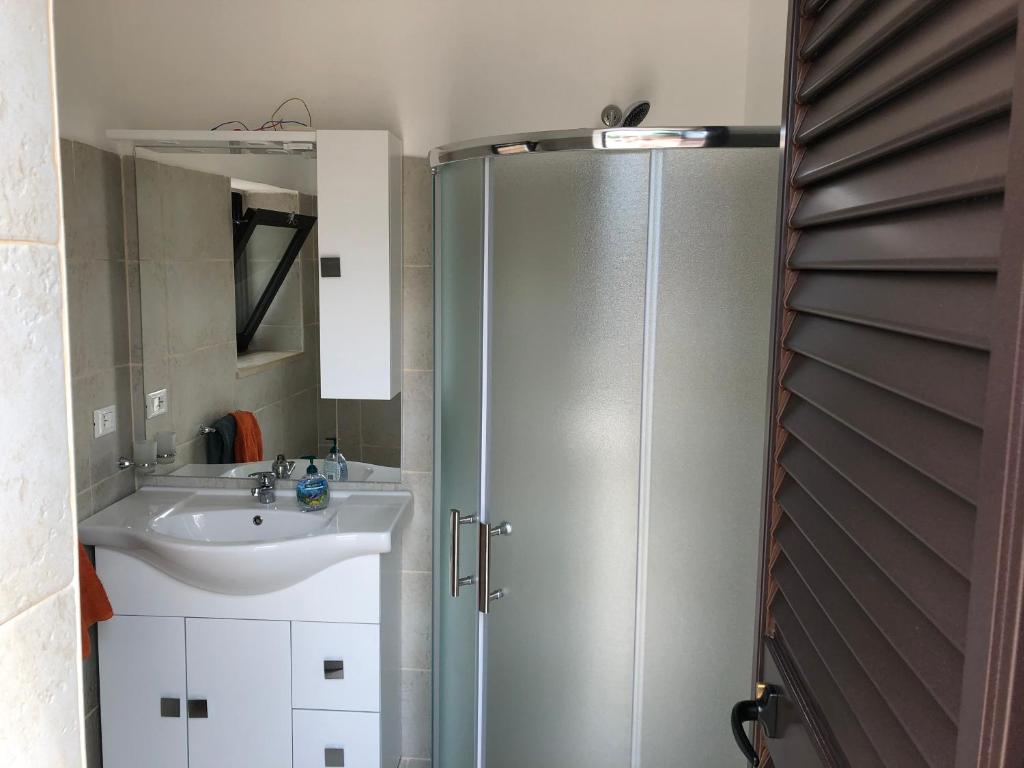 une salle de bain avec douche et lavabo dans l'établissement TRULLO PARCOMONSIGNORE CON PISCINA PRIVATA, à San Vito dei Normanni