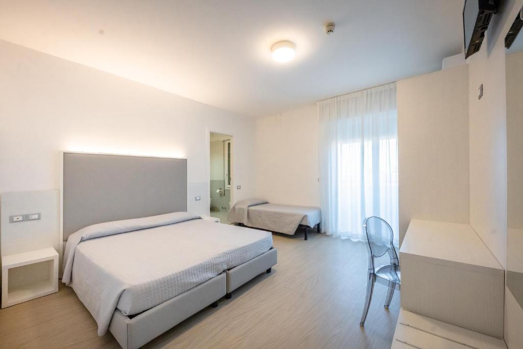 - une chambre avec 2 lits et une chaise dans l'établissement Hotel Portofino, à Caorle