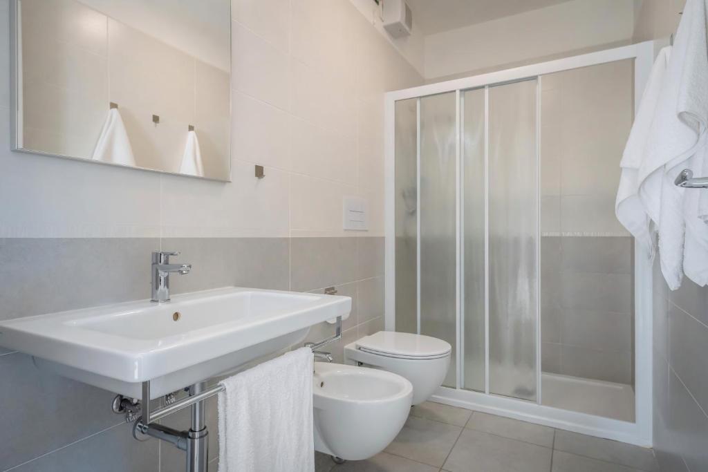 une salle de bain blanche avec un lavabo et des toilettes dans l'établissement Hotel Portofino, à Caorle
