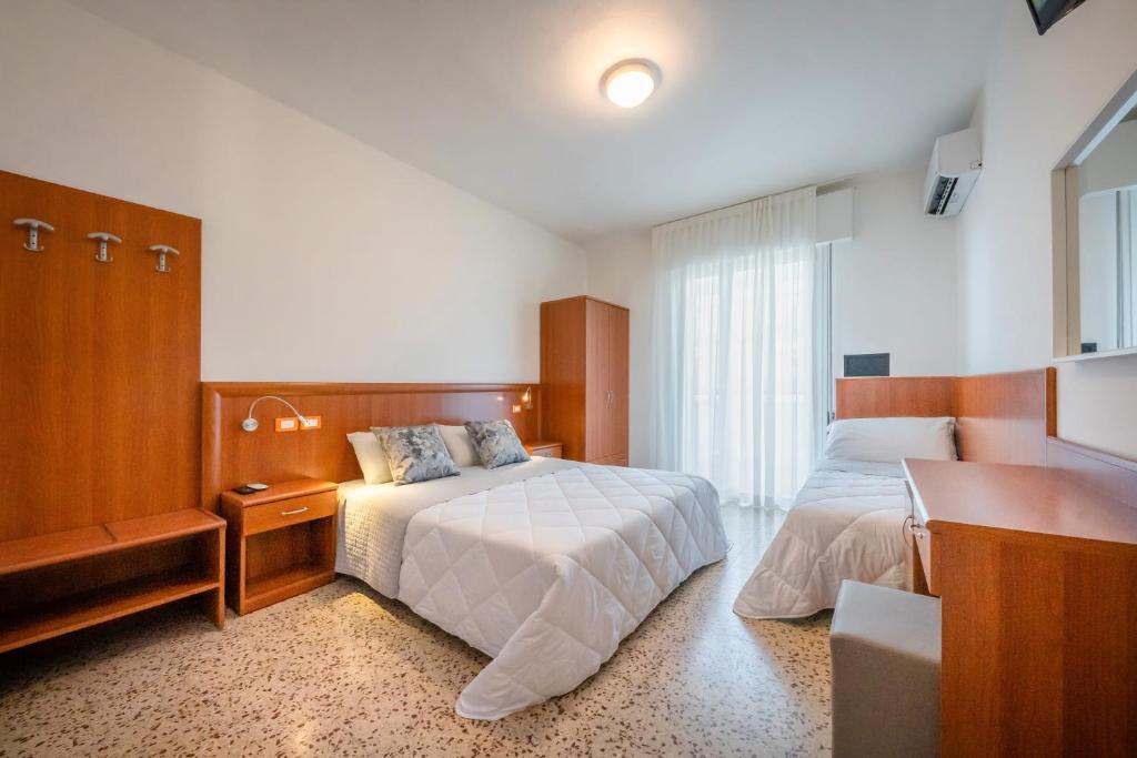 une chambre d'hôtel avec deux lits et un bureau dans l'établissement Hotel Portofino, à Caorle
