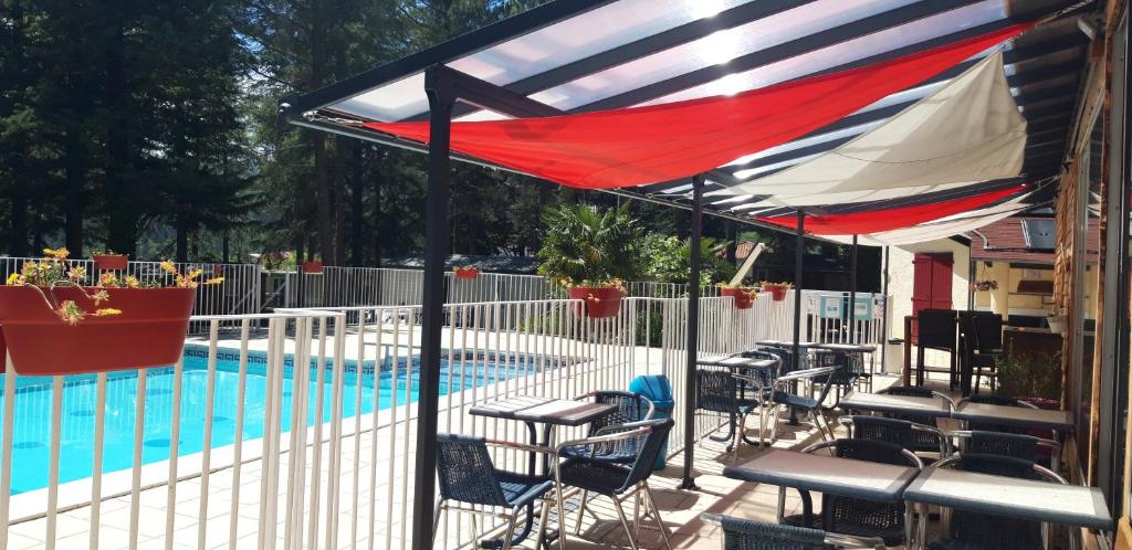 un auvent au-dessus d'une piscine avec des chaises et une table dans l'établissement Camping la Source, à Sournia