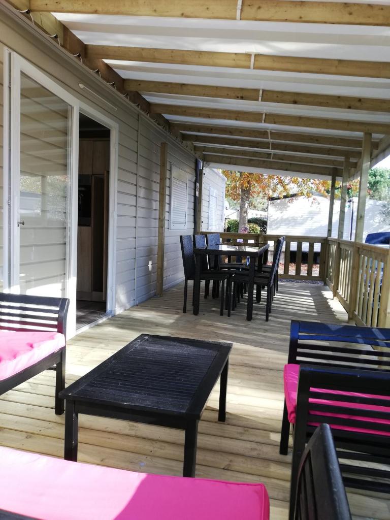 une terrasse en bois avec une table et des chaises dessus dans l'établissement MOBILHOME GASTES LANDES, à Gastes