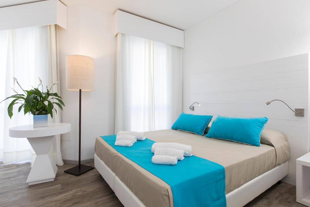 une chambre avec un grand lit avec des oreillers bleus dans l'établissement Lu' Hotel Maladroxia, à SantʼAntìoco