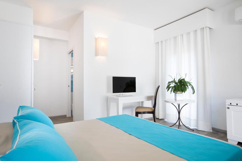 une chambre blanche avec un lit et un bureau dans l'établissement Lu' Hotel Maladroxia, à SantʼAntìoco
