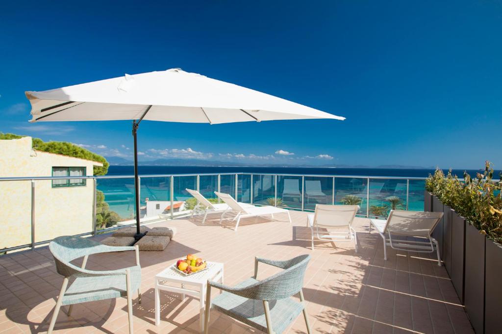 un patio avec une table, des chaises et un parasol dans l'établissement Lu' Hotel Maladroxia, à SantʼAntìoco