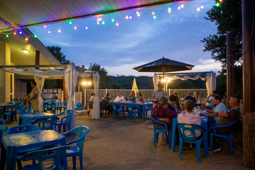 un groupe de personnes assises à des tables dans un restaurant dans l'établissement Camping du Lac de Saint-Pardoux, à Saint-Pardoux