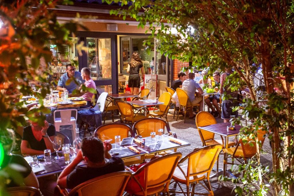 un groupe de personnes assises à des tables à l'extérieur d'un restaurant dans l'établissement Camping de la Bageasse, à Brioude