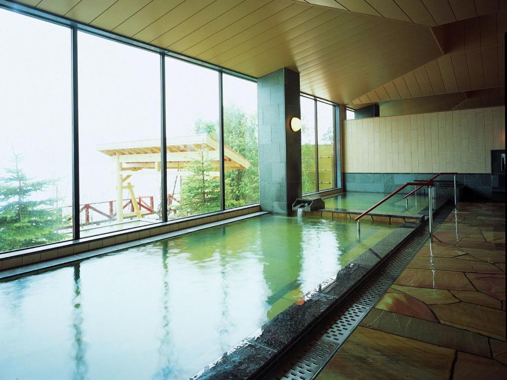 - une piscine d'eau dans un bâtiment avec fenêtres dans l'établissement Sapporo's Secret Onsen Sanctuary Marukoma Onsen Ryokan, à Chitose