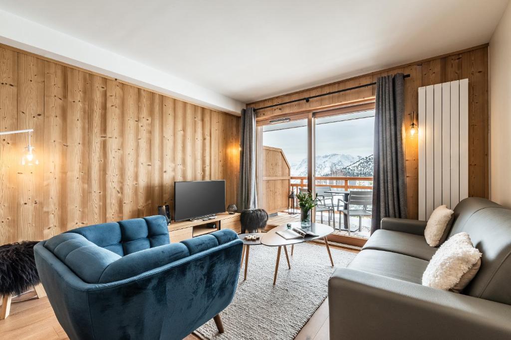 un salon avec un canapé et une télévision dans l'établissement Residence Hameau de Clotaire Alpe d'Huez - by EMERALD STAY, à L'Alpe-d'Huez