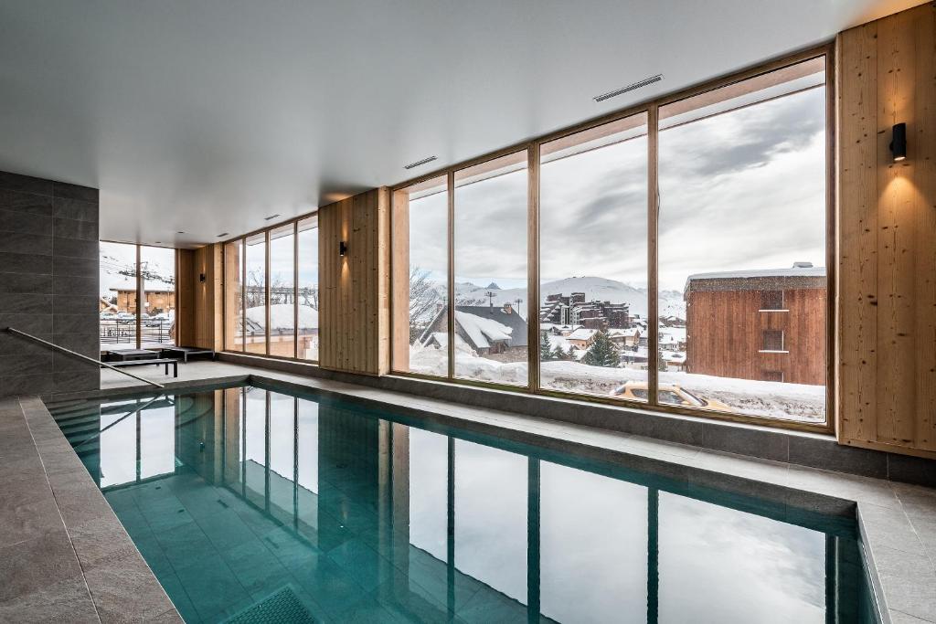 - une piscine avec vue sur les montagnes enneigées dans l'établissement Residence Hameau de Clotaire Alpe d'Huez - by EMERALD STAY, à L'Alpe-d'Huez