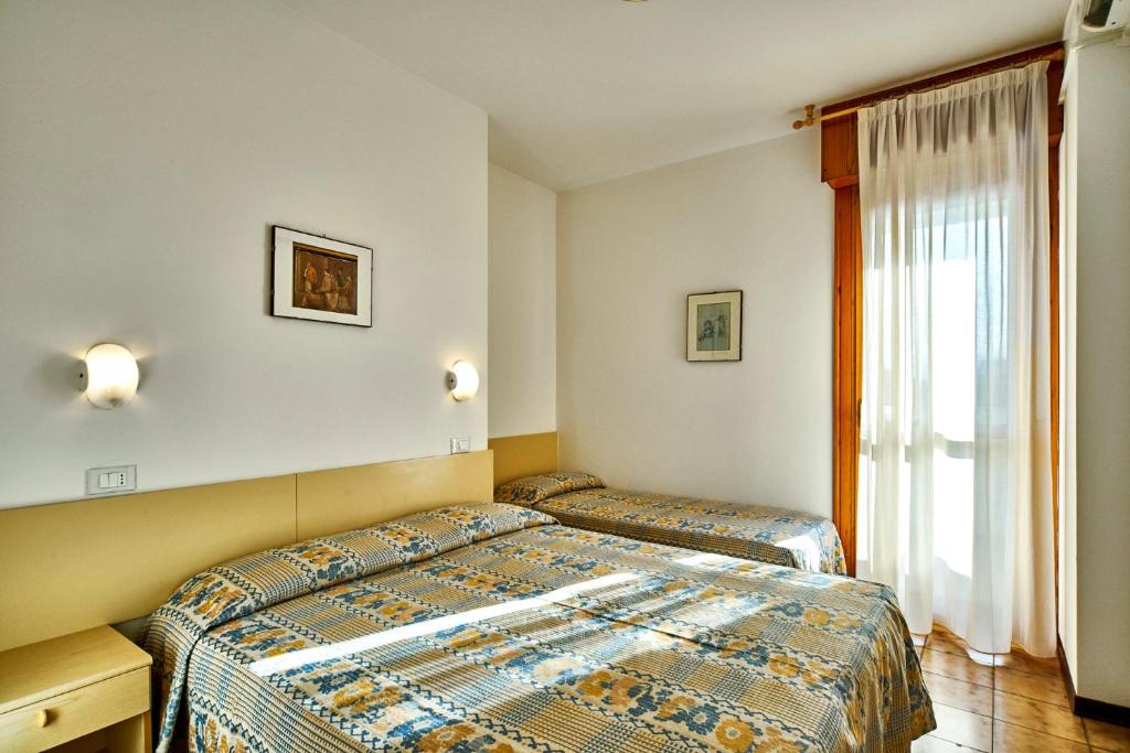 une chambre avec deux lits et une fenêtre dans l'établissement Residence Columbia, à Bibione