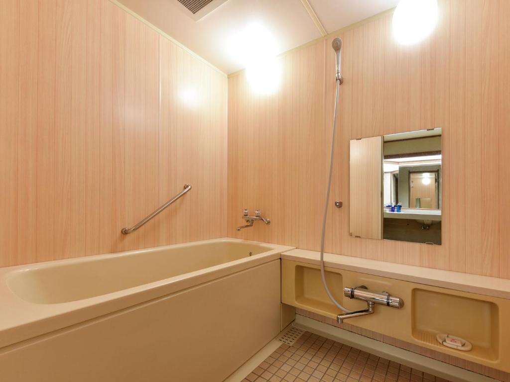 une salle de bain avec une baignoire et un miroir dans l'établissement Hanamomiji, à Jozankei