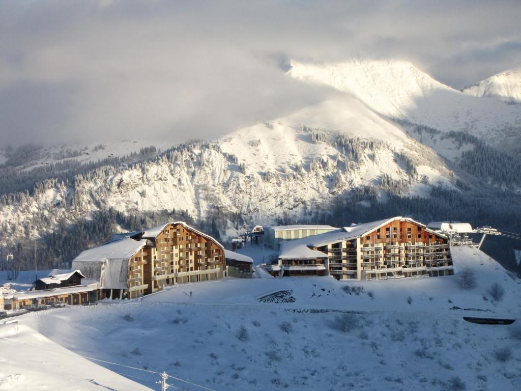 un complexe dans la neige avec une montagne en arrière-plan dans l'établissement Giffre, à Samoëns
