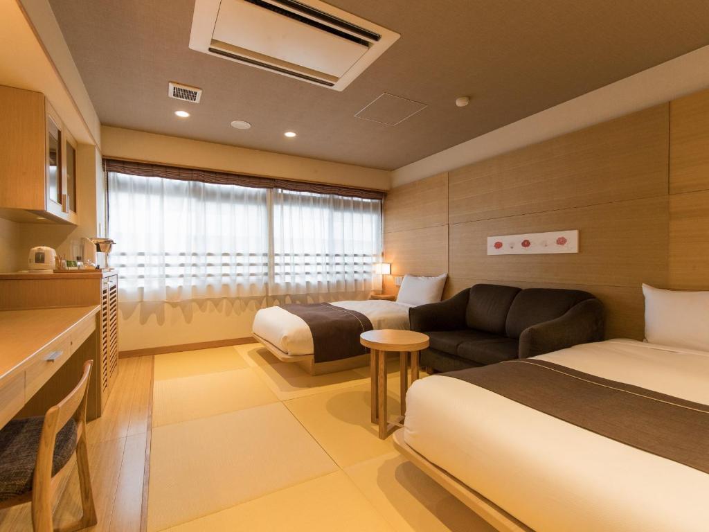 une chambre d'hôtel avec deux lits et un canapé dans l'établissement Hana Beppu, à Beppu