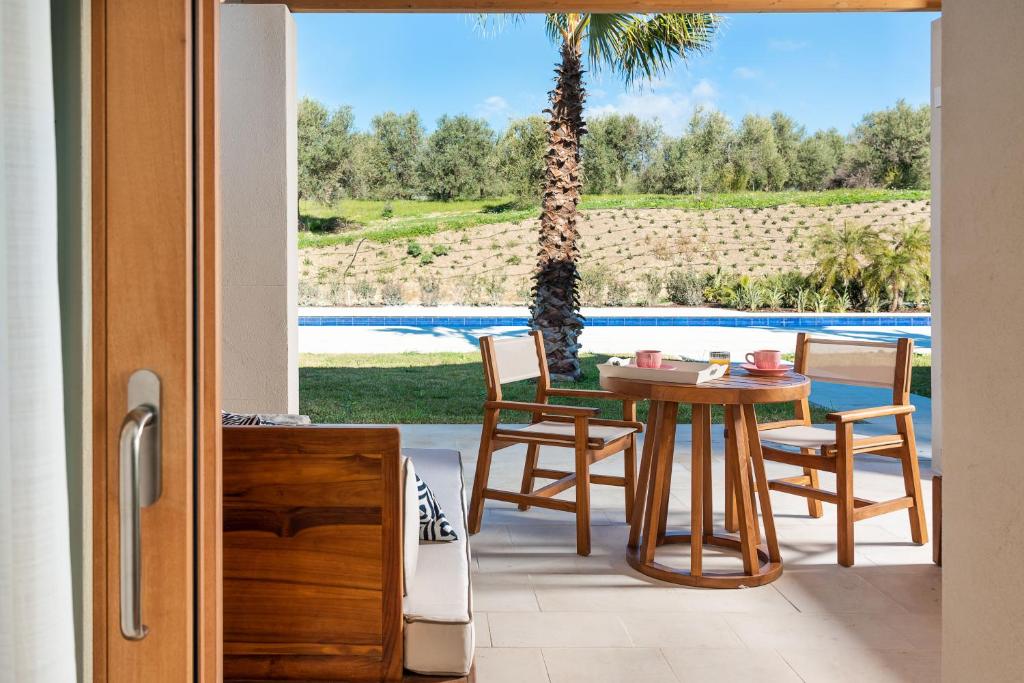 un patio avec une table, des chaises et un palmier dans l'établissement Il San Corrado di Noto, à Noto