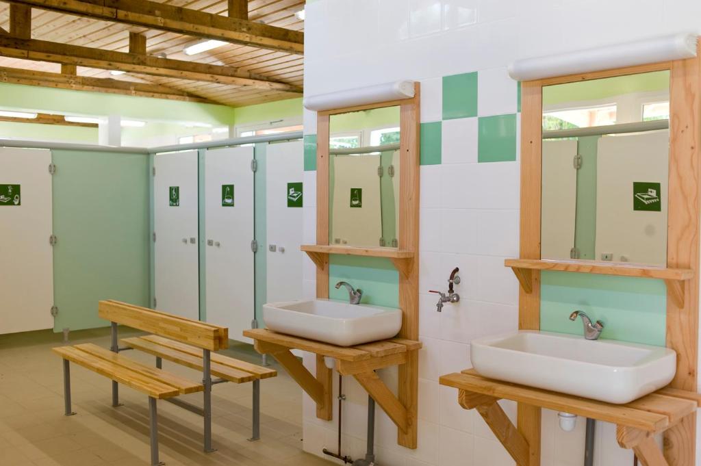 La salle de bains est pourvue de 2 lavabos, de miroirs et d'un banc. dans l'établissement Camping le Nid du Parc, à Villars-les-Dombes