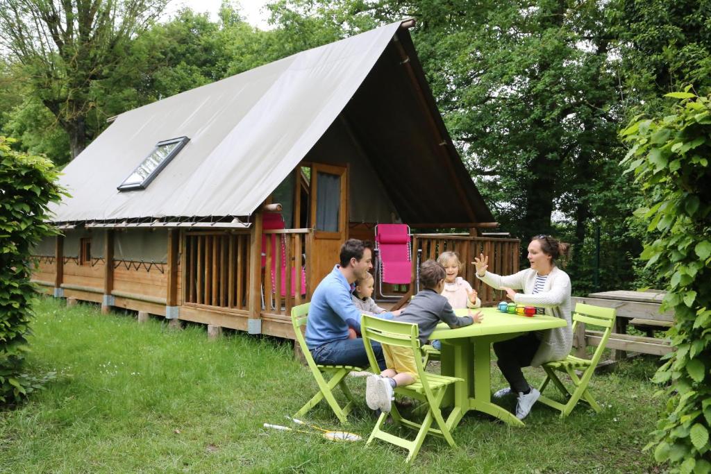 une famille assise à une table devant une cabine dans l'établissement Camping le Nid du Parc, à Villars-les-Dombes