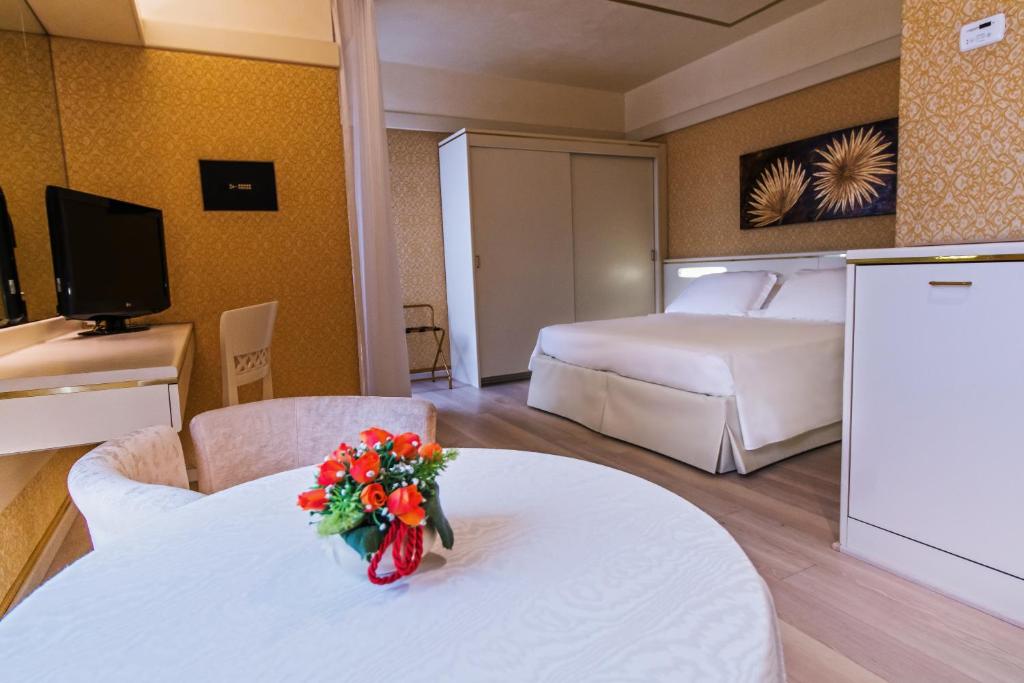 une chambre d'hôtel avec un lit et une table avec des fleurs dans l'établissement Hotel Bristol, à Sottomarina