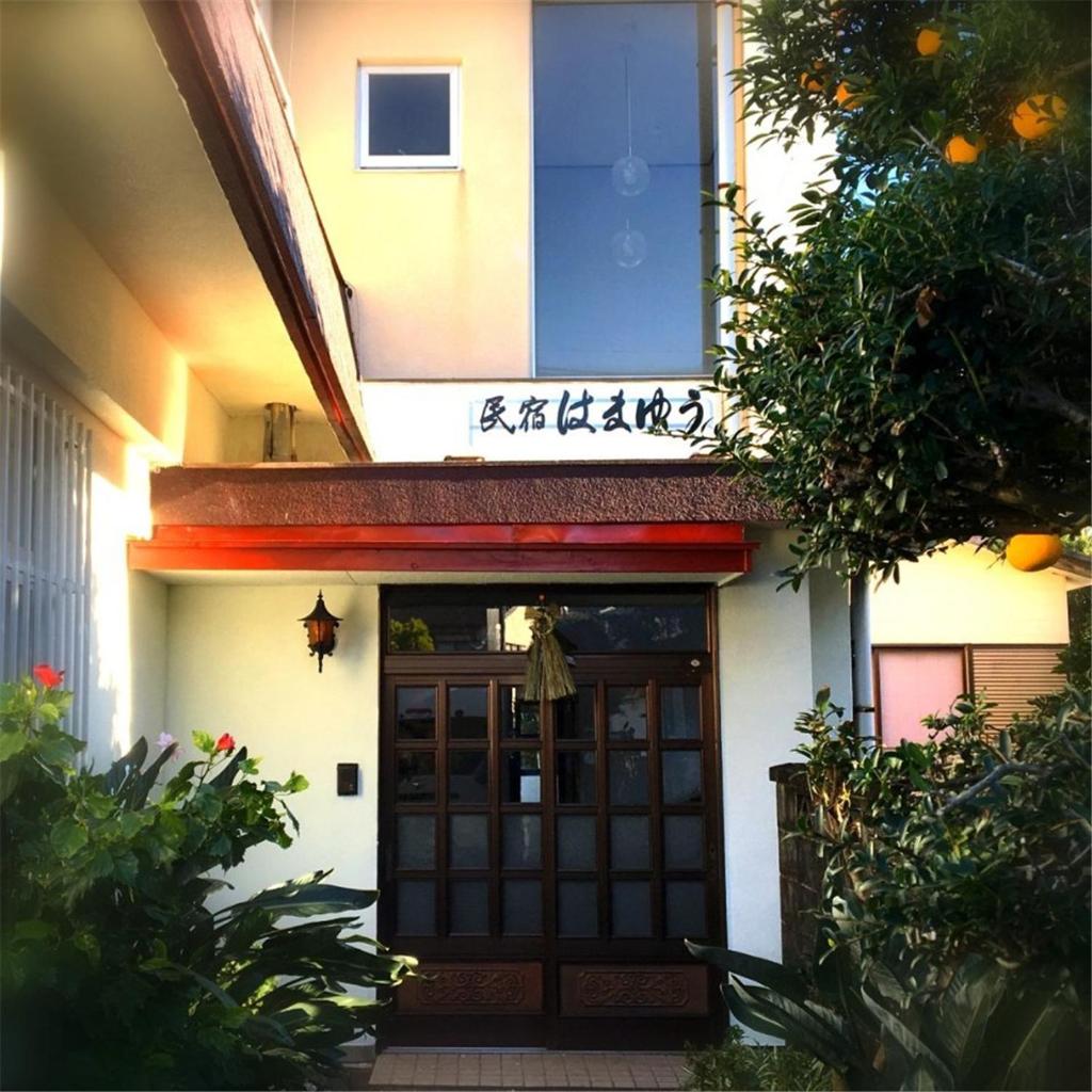 une porte d'entrée d'un bâtiment avec un panneau au-dessus de celui-ci dans l'établissement Hamayuu, à Higashiizu