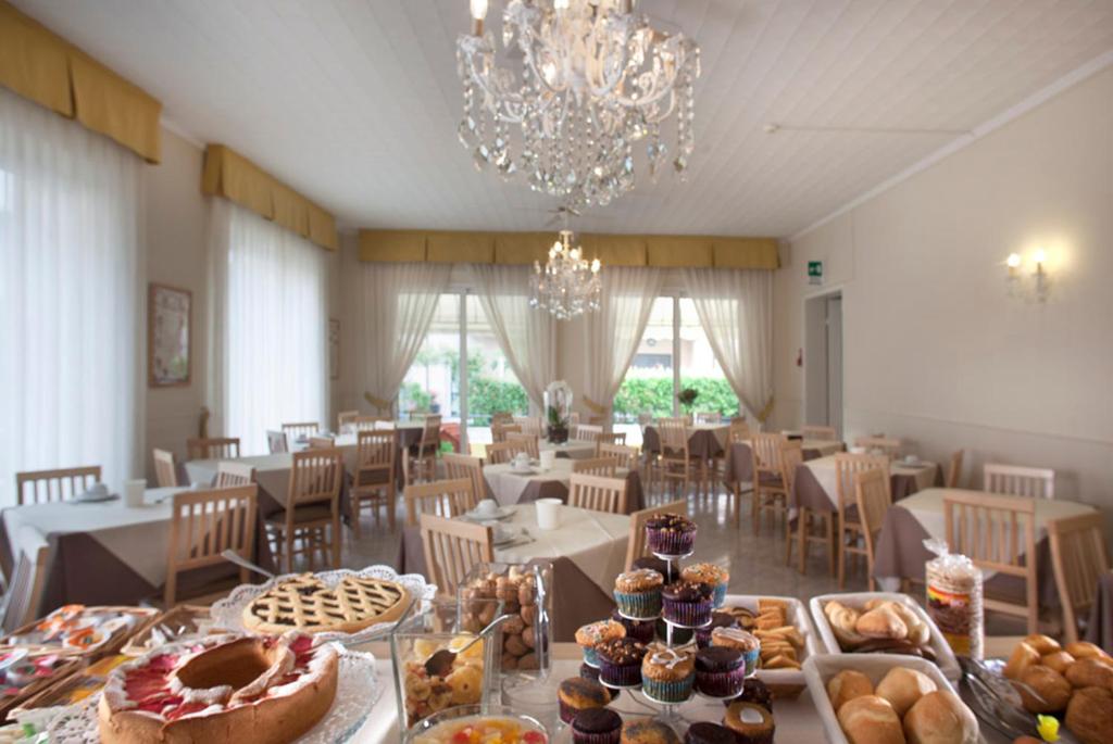 une salle à manger avec une table remplie de pâtisseries dans l'établissement Hotel Villa Perazzini, à Rimini