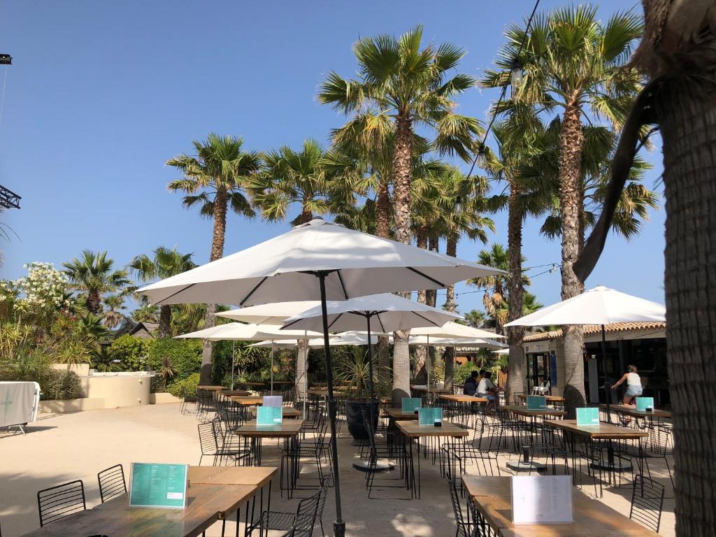 un groupe de tables et de chaises avec parasols et palmiers dans l'établissement Best Holiday Port Grimaud, à Grimaud