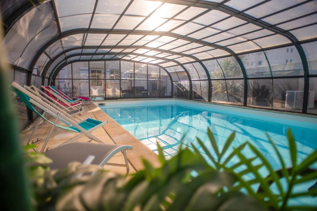 une piscine intérieure avec des chaises et un bâtiment dans l'établissement GITE LES BALISES-TRIBORD-SAINT GILLES CROIX DE VIE, à Saint-Gilles-Croix-de-Vie