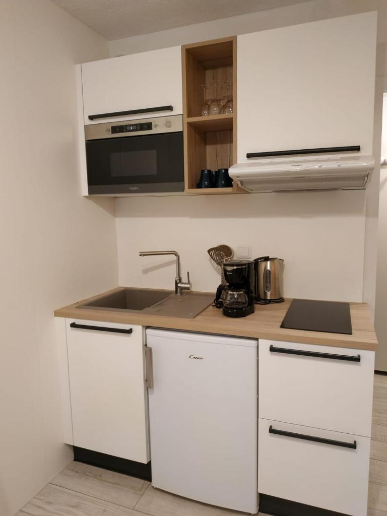 une cuisine blanche avec un évier et un micro-ondes dans l'établissement Cocon d'altitude - Studio avec vue sur les pistes, aux Orres