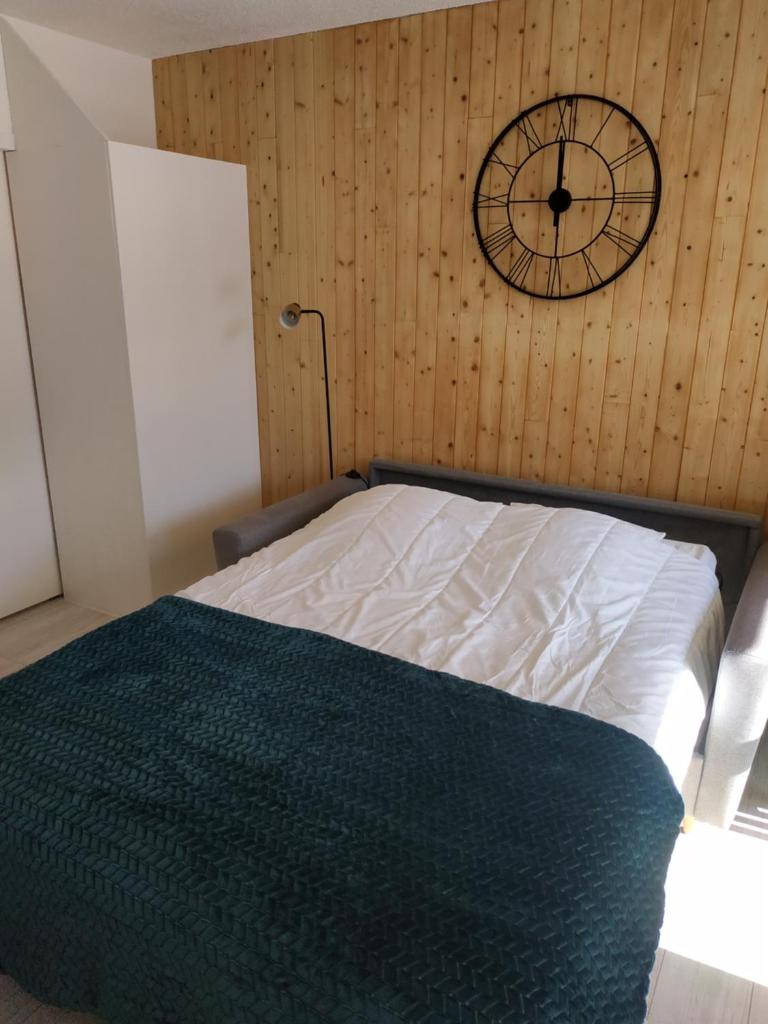 une chambre avec un lit et une horloge au mur dans l'établissement Cocon d'altitude - Studio avec vue sur les pistes, aux Orres