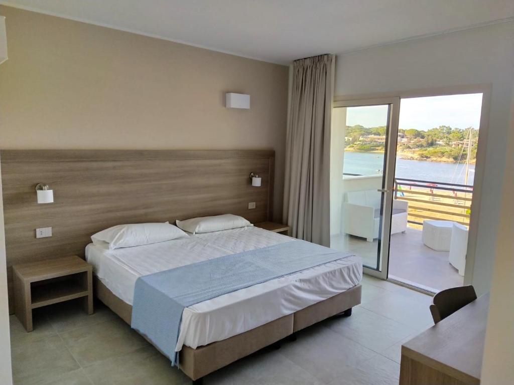 une chambre avec un grand lit et un balcon dans l'établissement Club Esse Cala Bitta, à Baja Sardinia