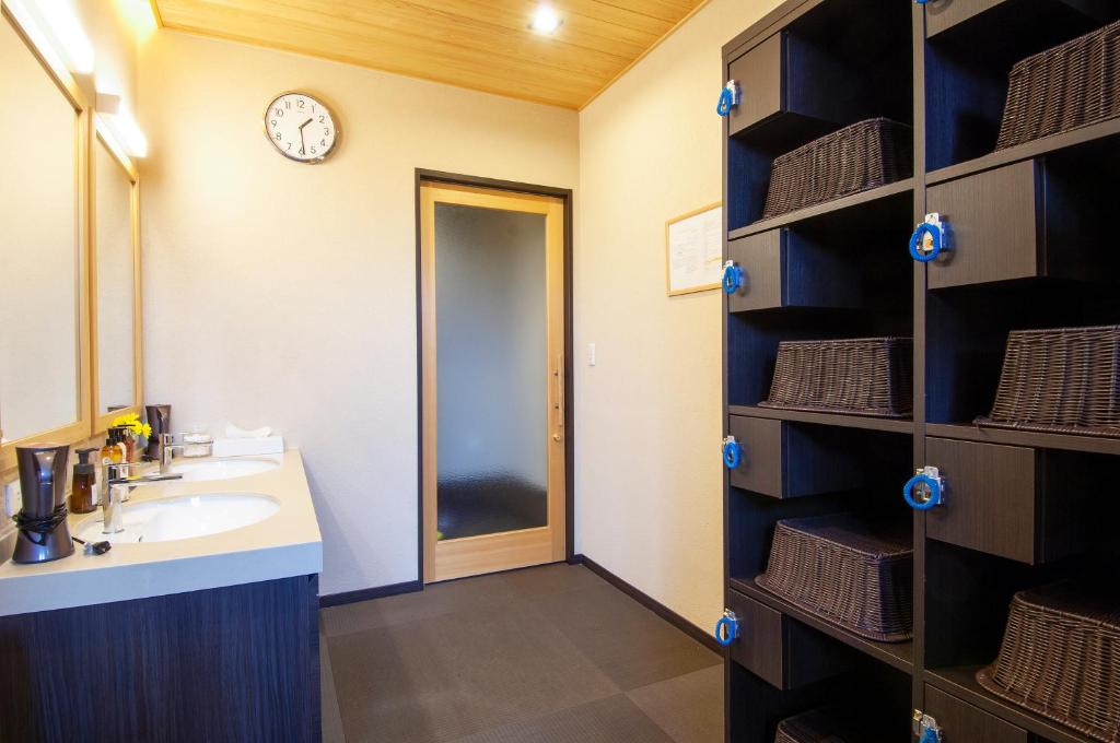 La salle de bains est pourvue d'un lavabo et d'une horloge murale. dans l'établissement Oyado Yukizumi, à Kusatsu