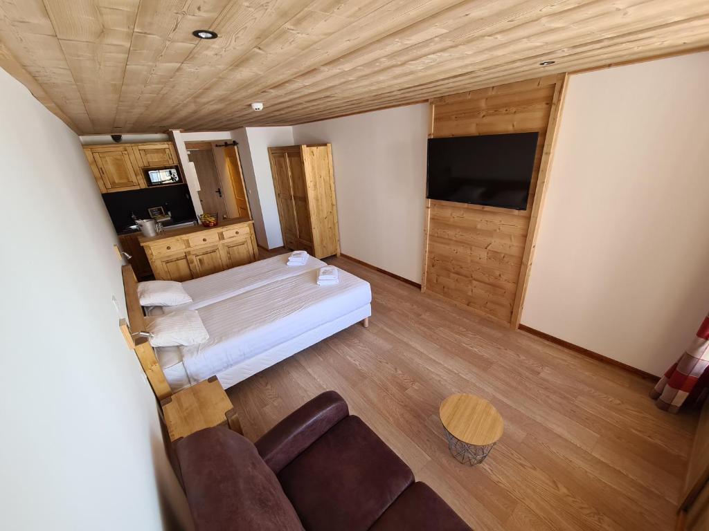 une chambre avec un lit, un canapé et une télévision dans l'établissement Chalet Le Granitic, aux Menuires