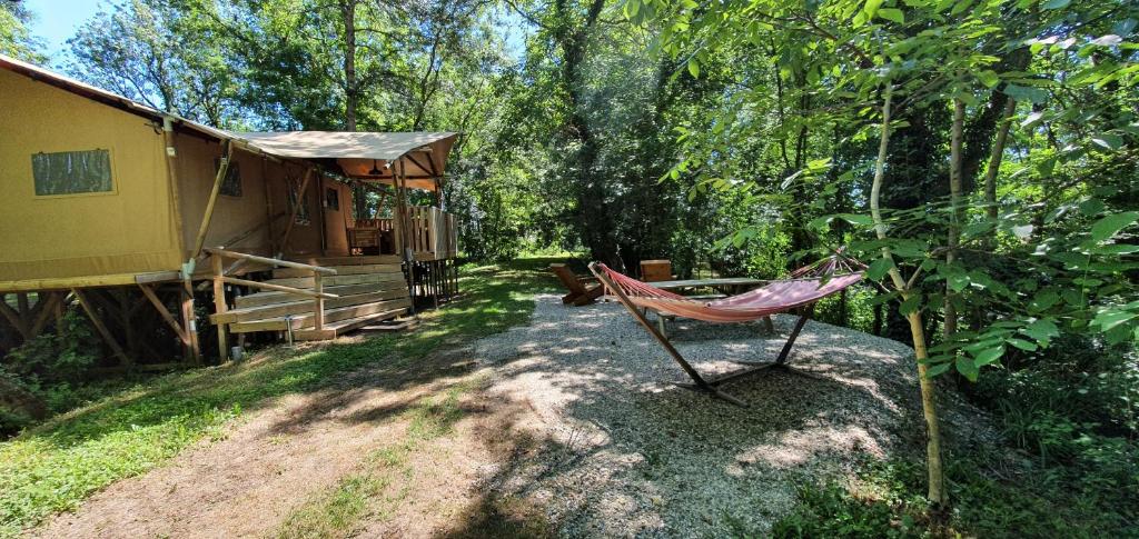 - un hamac rouge assis devant une cabine dans l'établissement Les lodges du Moulin, à Saint-Laurent