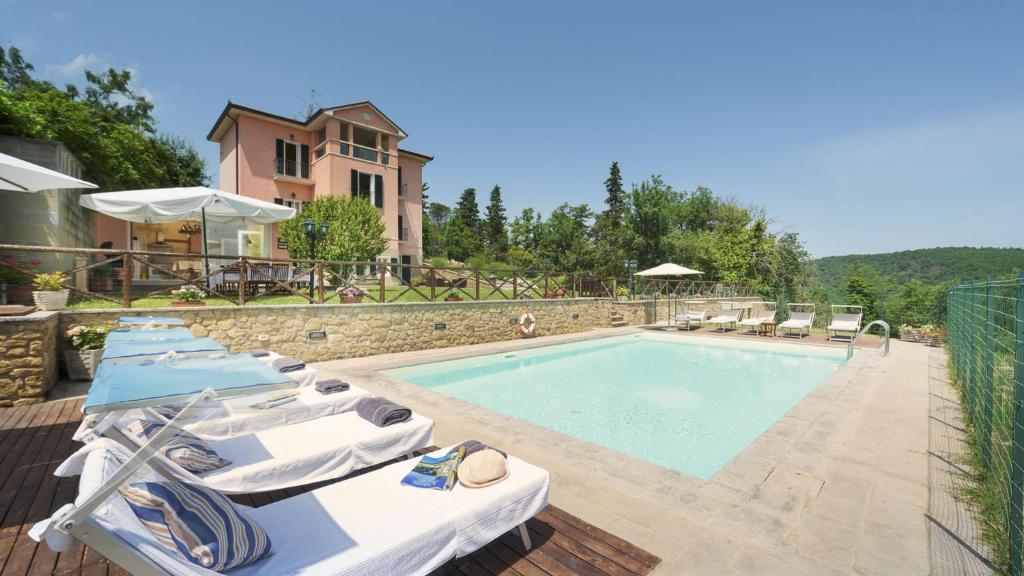 une piscine avec des chaises longues et une maison dans l'établissement VILLA VITTORIA D'ANGHIARI 7&3, Emma Villas, à Anghiari