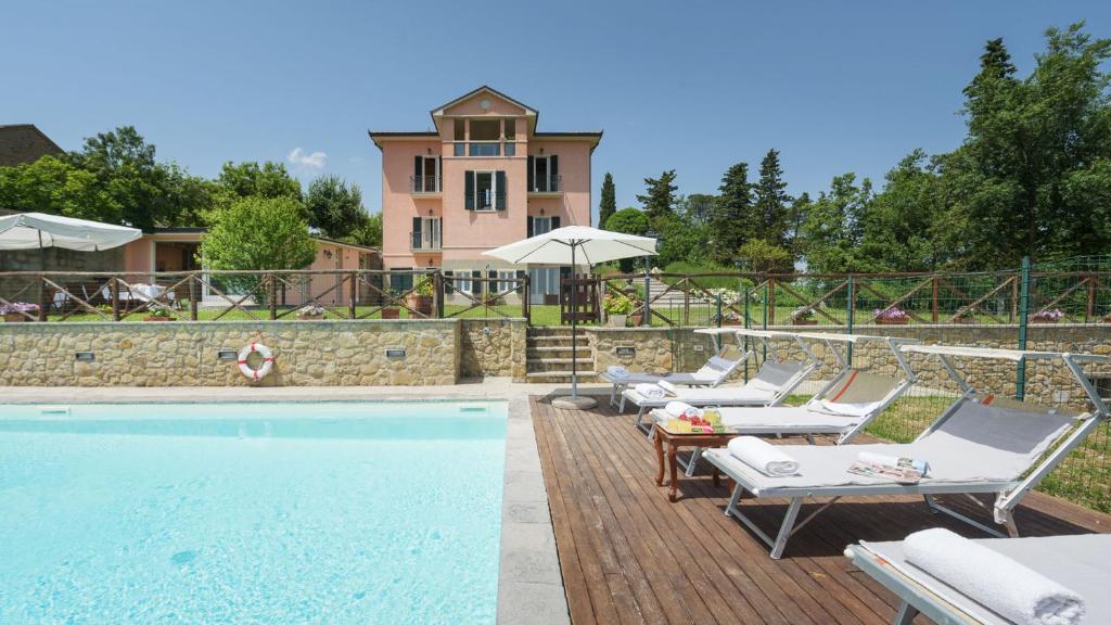 une piscine avec des chaises et une maison en arrière-plan dans l'établissement VILLA VITTORIA D'ANGHIARI 7&3, Emma Villas, à Anghiari