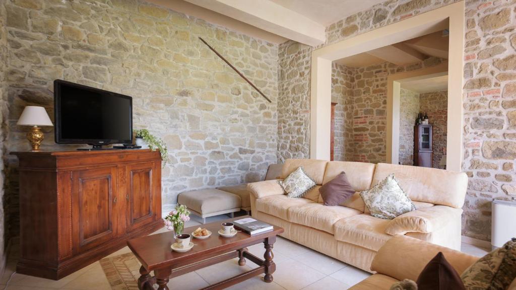 un salon avec un canapé et une télévision dans l'établissement VILLA VITTORIA D'ANGHIARI 7&3, Emma Villas, à Anghiari