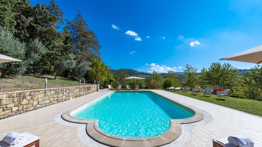une piscine dans une arrière-cour avec un mur en pierre dans l'établissement BORGO COLLE RIDENTE 13, Emma Villas, à Camerino