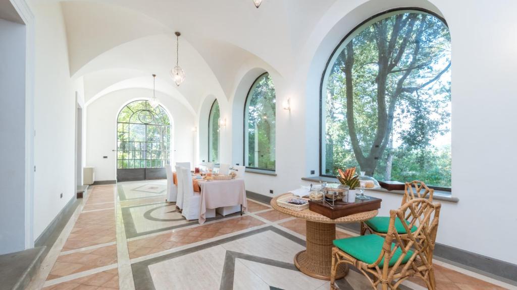- un salon avec des fenêtres cintrées, une table et des chaises dans l'établissement BORGO COLLE RIDENTE 13, Emma Villas, à Camerino