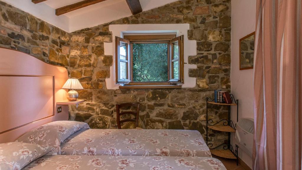 une chambre avec un lit et un mur en pierre dans l'établissement Casa Torrione 14, Emma Villas, à Paciano