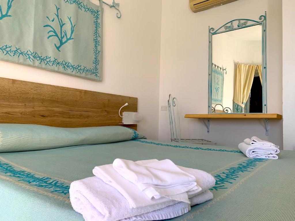 - un lit avec des serviettes et un miroir dans l'établissement Club Esse Shardana, à Santa Teresa Gallura